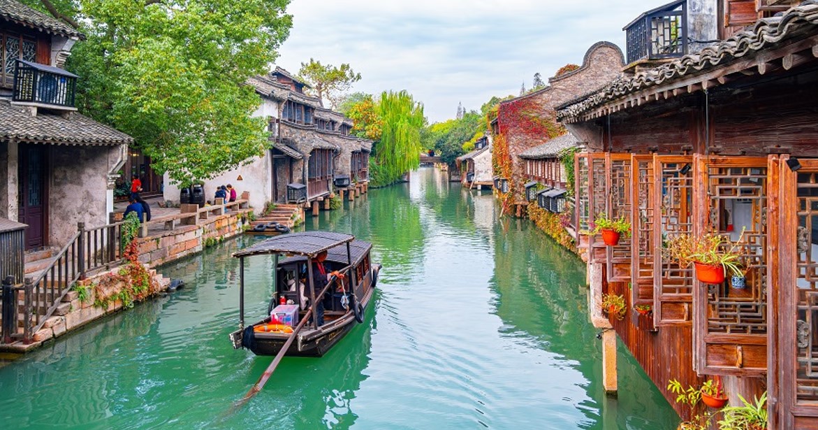 Water town canal scene in Jiangnan — traditional whitewashed buildings lining a serene waterway
